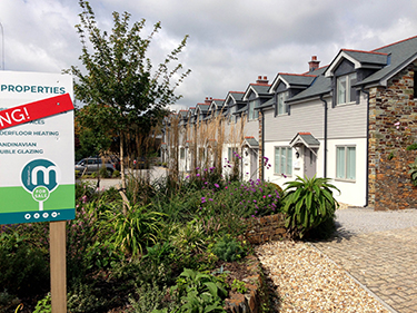 view of small building development with planting and one property remaining for sale sign